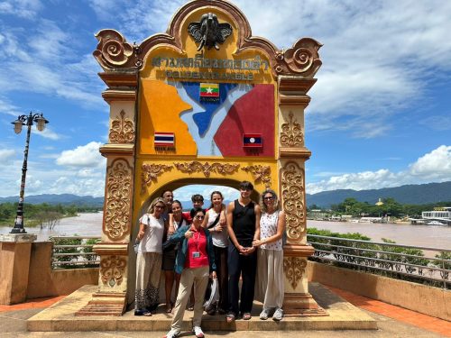 Group photo under the Golden Triangle monument showing the borders of Thailand, Laos, and Myanmar during a private tour.
