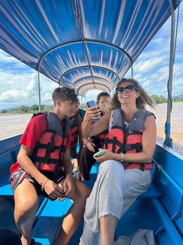 Happy travelers wearing life jackets on a private motorboat cruise along the Mekong River in the Golden Triangle.