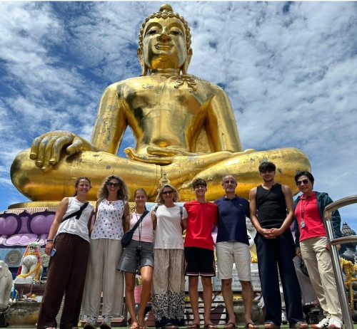 Tour group posing in front of the magnificent golden Big Buddha statue at Wat Phra That Pha Ngao near Chiang Rai.