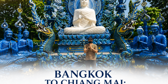 A man performs a traditional Thai Wai greeting in front of a majestic, intricate blue temple featuring a large white seated Buddha, representing a highlight of a private Bangkok to Chiang Mai 7-day tour.